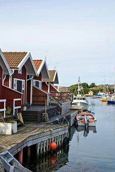 several boats are docked in the water next to red houses and buildings on stilts