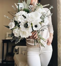 a woman holding a bouquet of white flowers