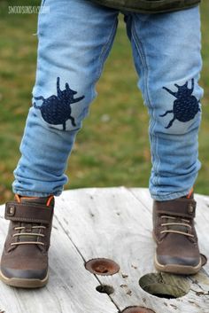 a child's feet with blue jeans and brown shoes on top of a wooden table