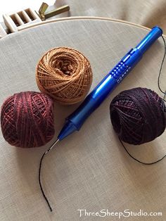 three balls of yarn sitting on top of a table next to a crochet hook