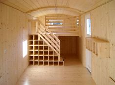 an empty room with wooden walls and shelves on the wall, along with a staircase leading up to the second floor