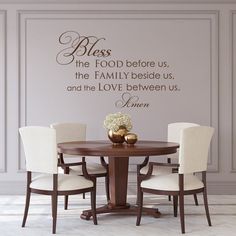 a dining room table with four chairs and a wall decal above it that says, bliss the food before us, the family beside us, and the love between us