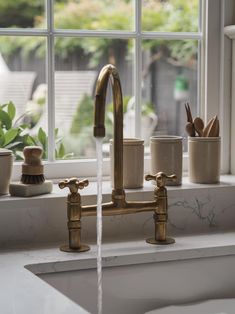 a faucet running water from a kitchen sink in front of a large window