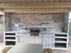 an outdoor kitchen that is made out of pallet wood and has built in cabinets