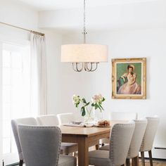 a dining room table with white chairs and a painting on the wall above it,