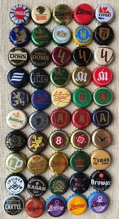 many different types of beer bottle caps are arranged on a table top with white linen