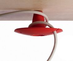 a red and white light hanging from the side of a wooden ceiling fixture with wires attached to it