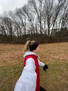 a woman in a red and white jacket is throwing a frisbee