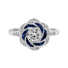 Artistry and sophistication come together in a flower ring with sapphires and diamonds from the Art Deco era. The ring features a round shape center which you can place any round diamond on it in a bezel setting surrounded by French French Cut Color Stones (you can select Blue Sapphire, Emerald, Ruby), round brilliant diamonds on shoulders add the sparkle to this beautiful ring. Ring Information Style: Art-deco Metal: 18K White Gold Weight: 4.35 g. (approx. total weight) Center Gemstones Type: D Art Deco Engagement Ring Sapphire, Engagement Rings With Sapphires, Vintage Sapphire Engagement Rings, Sapphire Diamond Rings, Art Deco Sapphire Engagement Ring, Diamond And Sapphire Engagement Ring, Blue Sapphire Wedding Ring, Diamond Sapphire Ring, Sapphire And Diamond Engagement Ring