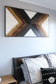 a bed with two pillows on top of it next to a painting above the headboard