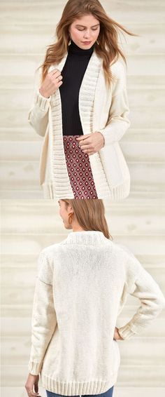 a woman standing in front of a wall wearing a white cardigan sweater and jeans