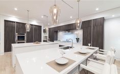 a large kitchen with white counter tops and wooden cabinets, along with modern lighting fixtures