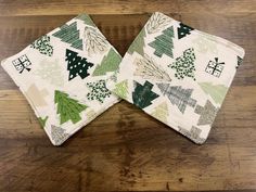 two green and white christmas tree napkins sitting on top of a wooden table