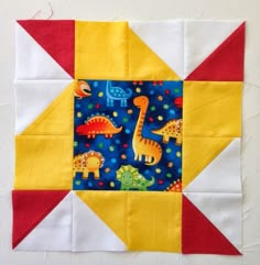 a patchwork quilt with dinosaurs and stars on the top, along with a block in the middle