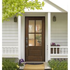 the front door of a white house with flowers