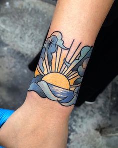 a person with a tattoo on their arm that has the sun and clouds in it