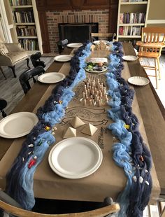 a long table with plates and napkins on it in front of a fire place