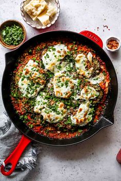 an iron skillet filled with eggs and vegetables on top of a white countertop