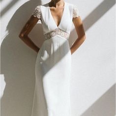 a woman standing in front of a white wall wearing a dress with lace on it