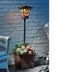 a lamp that is on top of a potted plant in front of a brick wall