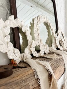 a mirror sitting on top of a wooden shelf next to a white cloth draped over it