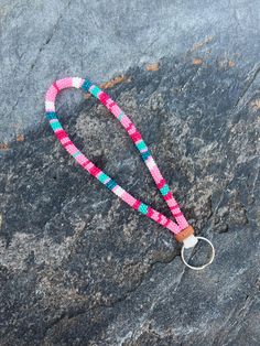 a pink and blue beaded lanyard on a rock