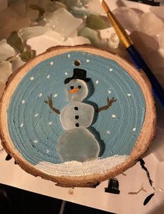 a wooden slice with a snowman painted on it