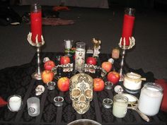 a table topped with candles and skulls surrounded by apples, milks and other items