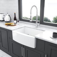 a white kitchen sink sitting under a window next to a counter top with wine bottles