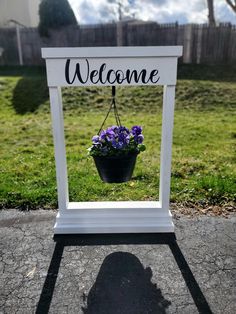 a welcome sign with purple flowers hanging from it