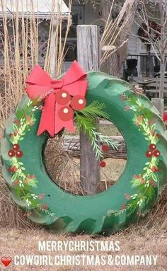 a christmas wreath sitting on top of a wooden post next to a fence with a red bow