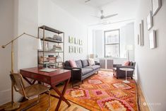 a living room filled with furniture and a red rug on top of a hard wood floor