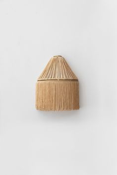 a wall mounted lamp with a straw shade on it's side and a white wall in the background