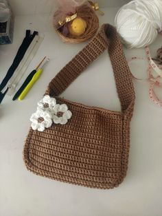 a crocheted purse sitting on top of a table next to yarn and scissors