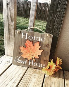 a wooden sign that says home sweet home with an orange maple leaf on the front