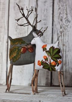 two deer figurines are standing next to each other on a wooden surface with white boards behind them