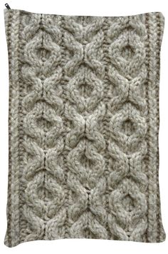 a white knitted cushion with an intricate design on the front and back side,