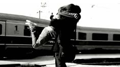 black and white photograph of a person on a skateboard in front of a train