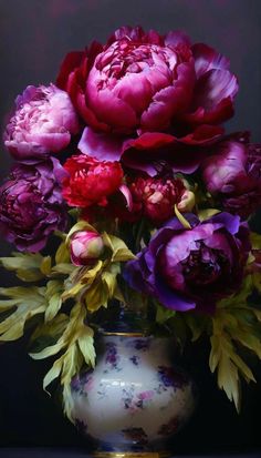 a vase filled with lots of purple and red flowers