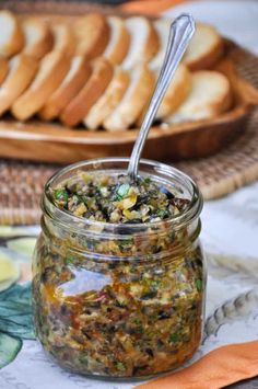 a glass jar filled with food sitting on top of a table next to sliced bread