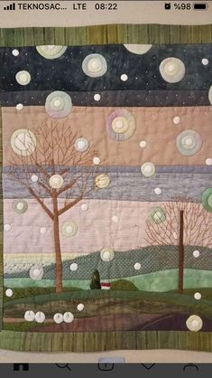 a quilted wall hanging with trees and moon in the sky