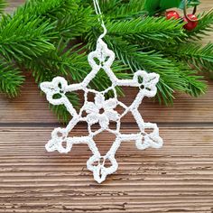 a crocheted snowflake ornament hanging from a christmas tree branch