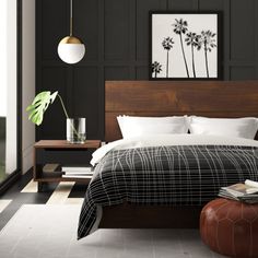 a bedroom with black walls and white bedding, brown foot stools, and a large window