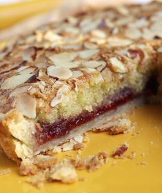 a piece of pie with almonds and jelly on it sitting on a yellow plate