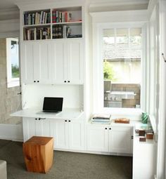 a living room with white furniture and bookshelves on the wall, along with a laptop computer