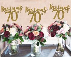 three vases filled with flowers sitting on top of a metal table next to a sign