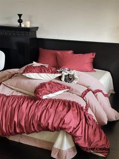 a bed with red sheets and pillows on it