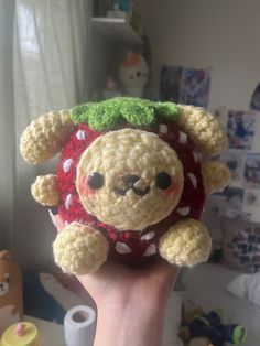 a hand holding a small crocheted stuffed animal in the shape of a strawberry