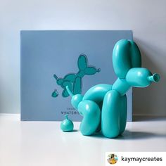 a blue balloon dog sitting on top of a table next to a box with the word happy birthday