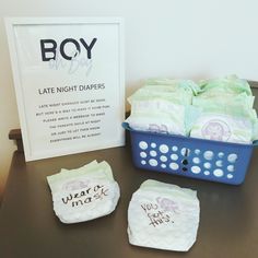 baby diapers are sitting on a table next to a basket and sign that says boy late night diapers